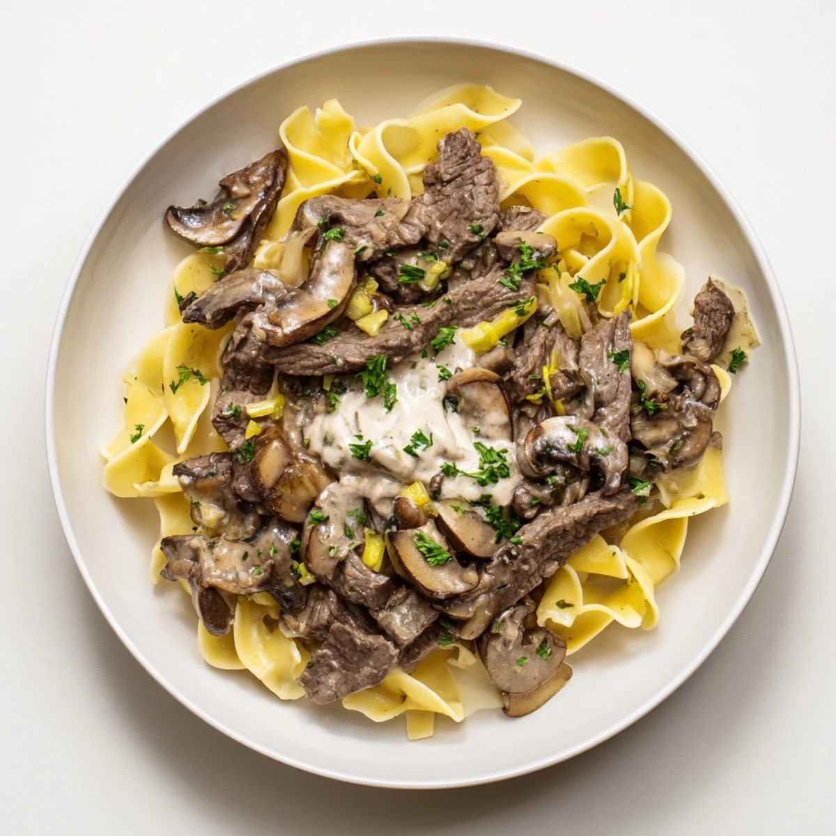 Tender beef stroganoff with creamy mushroom sauce over golden egg noodles, ready to eat.