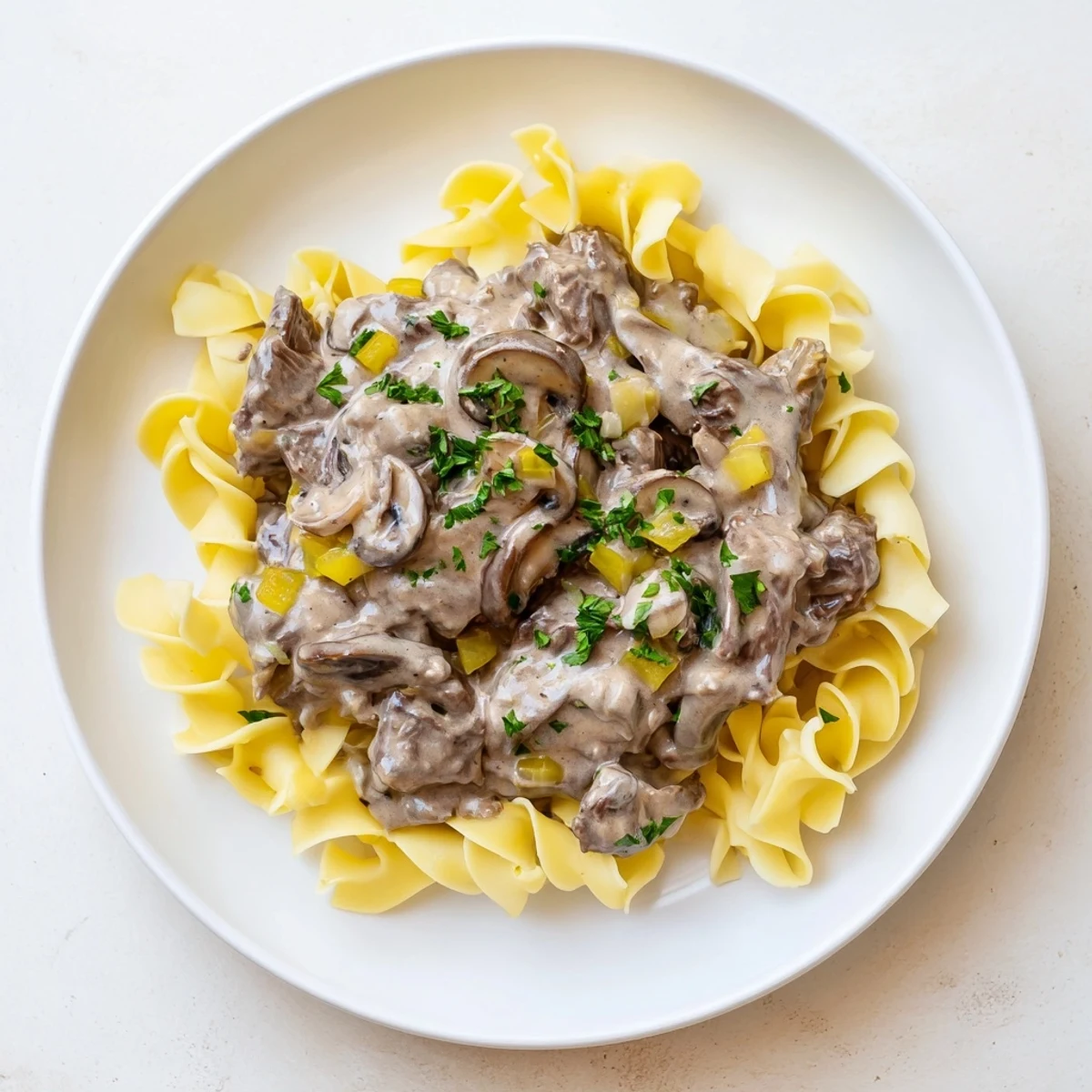 Close-up of savory beef stroganoff, featuring rich sauce swirling over a bed of egg noodles.