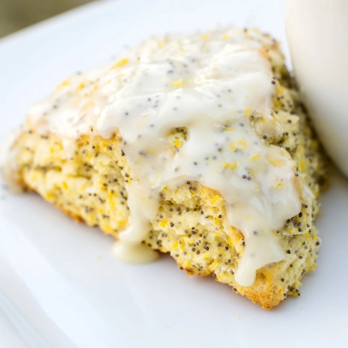 Golden brown Lemon Poppy Seed Scones stacked high, revealing fluffy insides and bright lemon zest in the crumb.