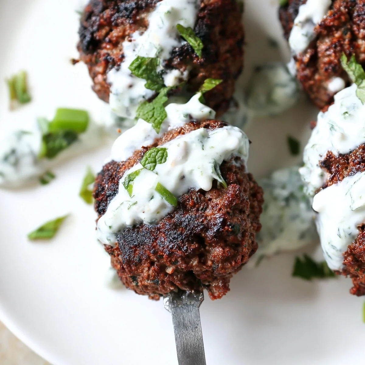 A platter of Beef Kofta Kebabs with Tzatziki Sauce features warm pita bread, sliced tomatoes, and red onions.