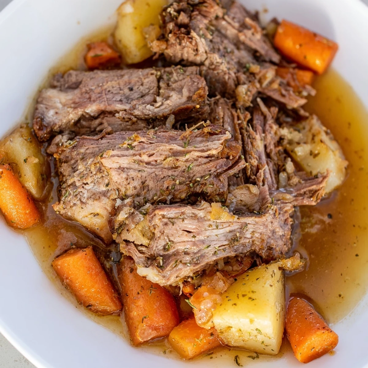 Fall-apart Slow Cooker Roast Beef on a bed of caramelized onions, celery, and aromatic herbs in the slow cooker.