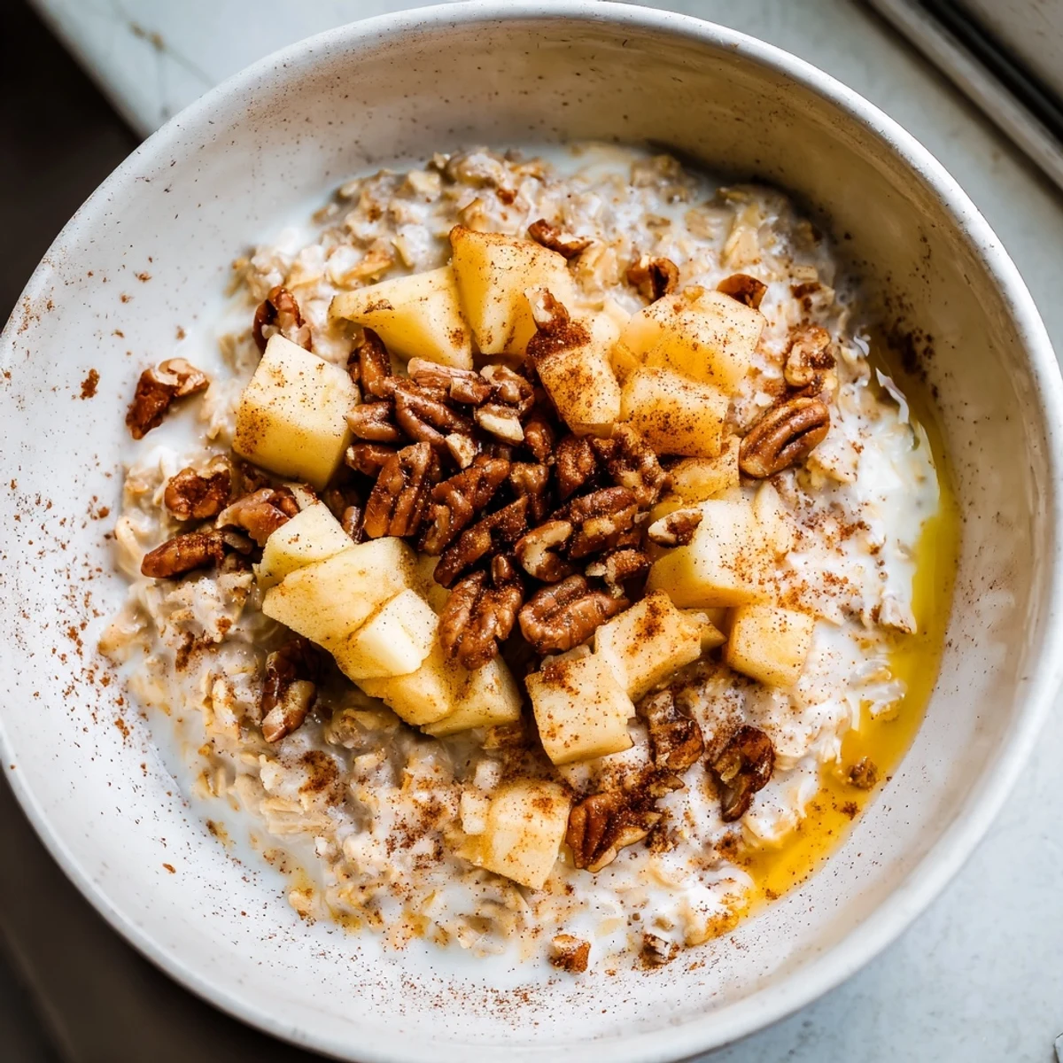 Wholesome Warm Apple Cinnamon Oatmeal with Pecans served in a rustic bowl, garnished with extra nuts and a drizzle of honey.