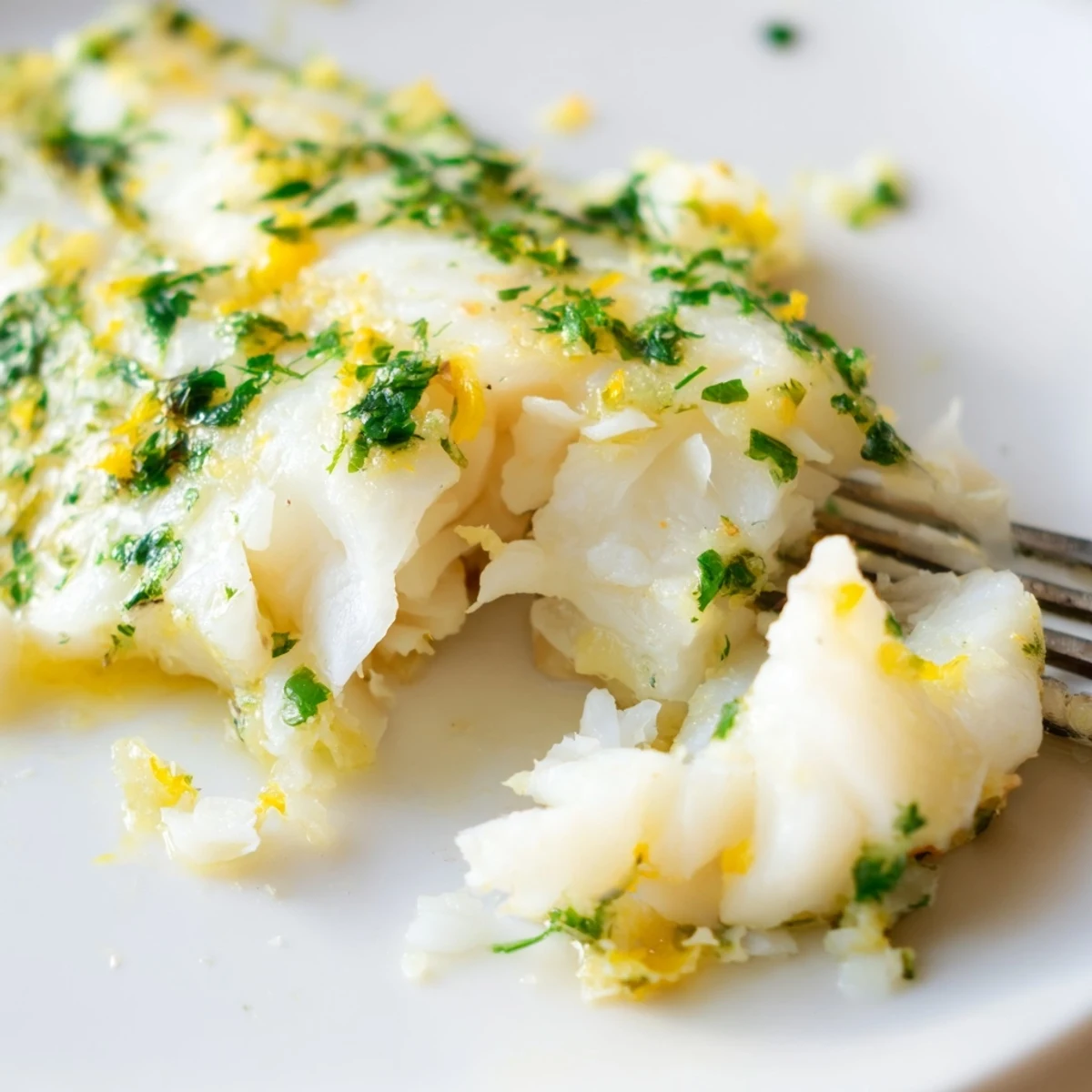 Savory Baked Cod with Lemon Herb Butter served with roasted potatoes and lemon slices.