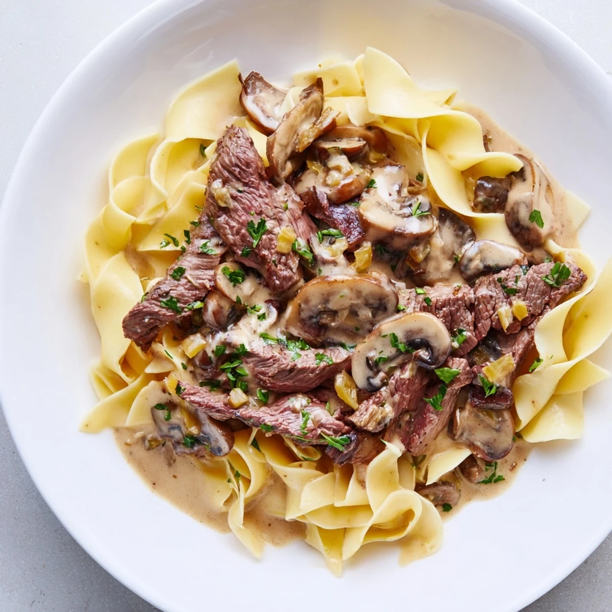 Savory Beef Stroganoff over Egg Noodles, served hot and garnished with parsley for a comforting dinner.