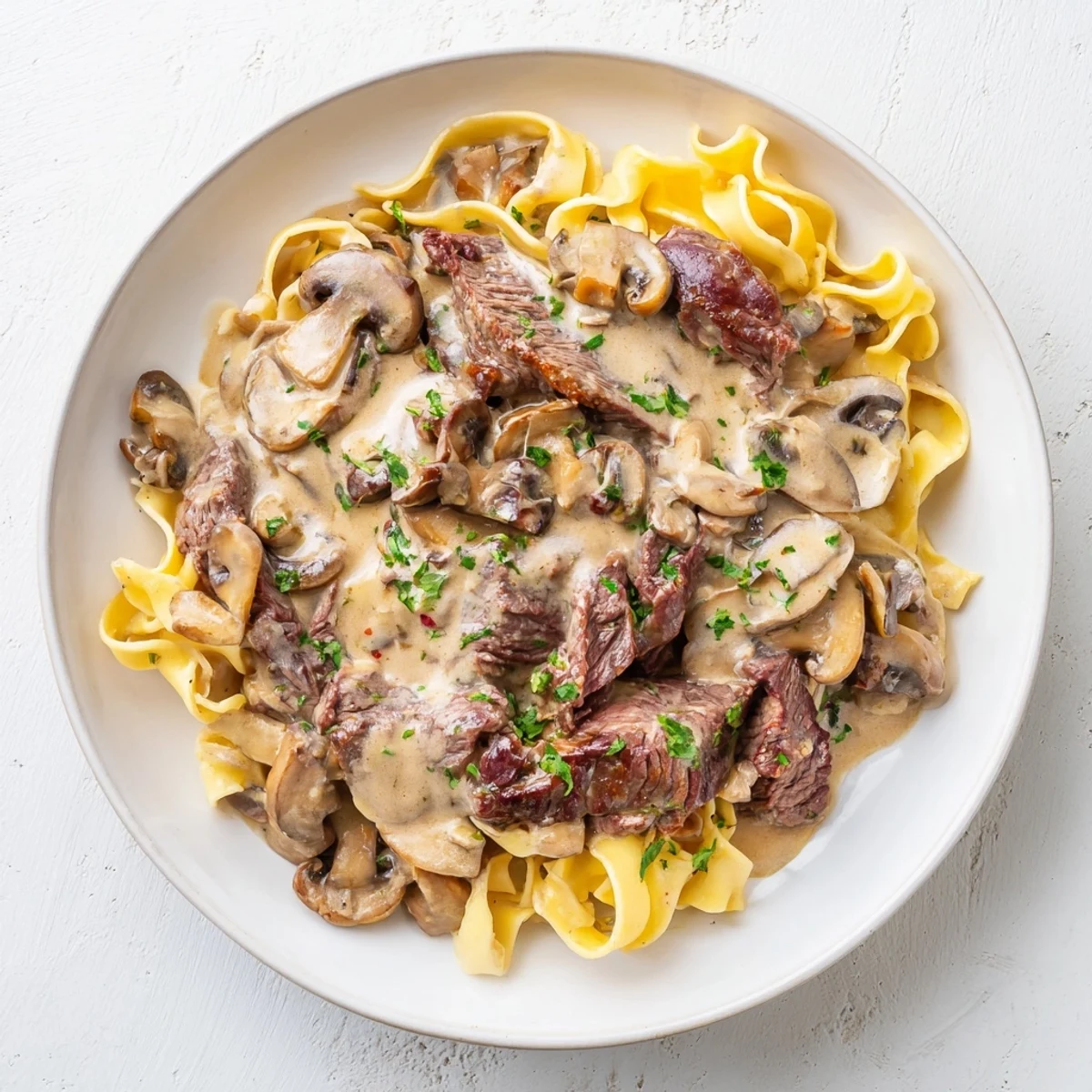 Platter of Beef Stroganoff over Egg Noodles, creamy sauce coating tender beef and mushrooms for a family meal.