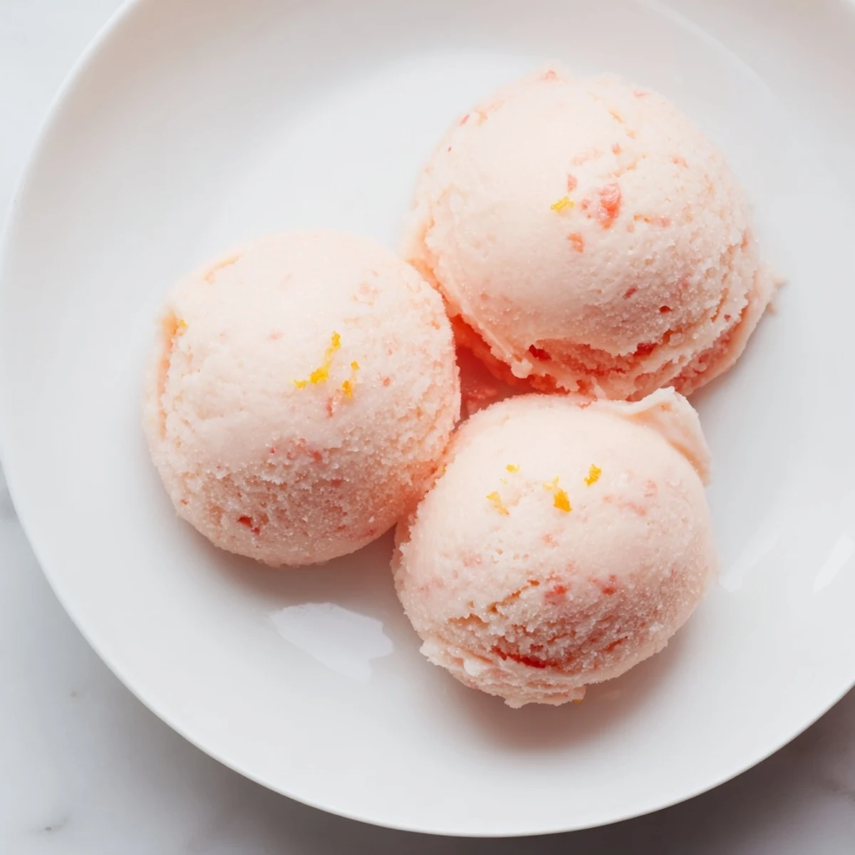 Freshly churned Pink Grapefruit Sorbet in a white bowl, garnished with mint for a refreshing summer dessert.