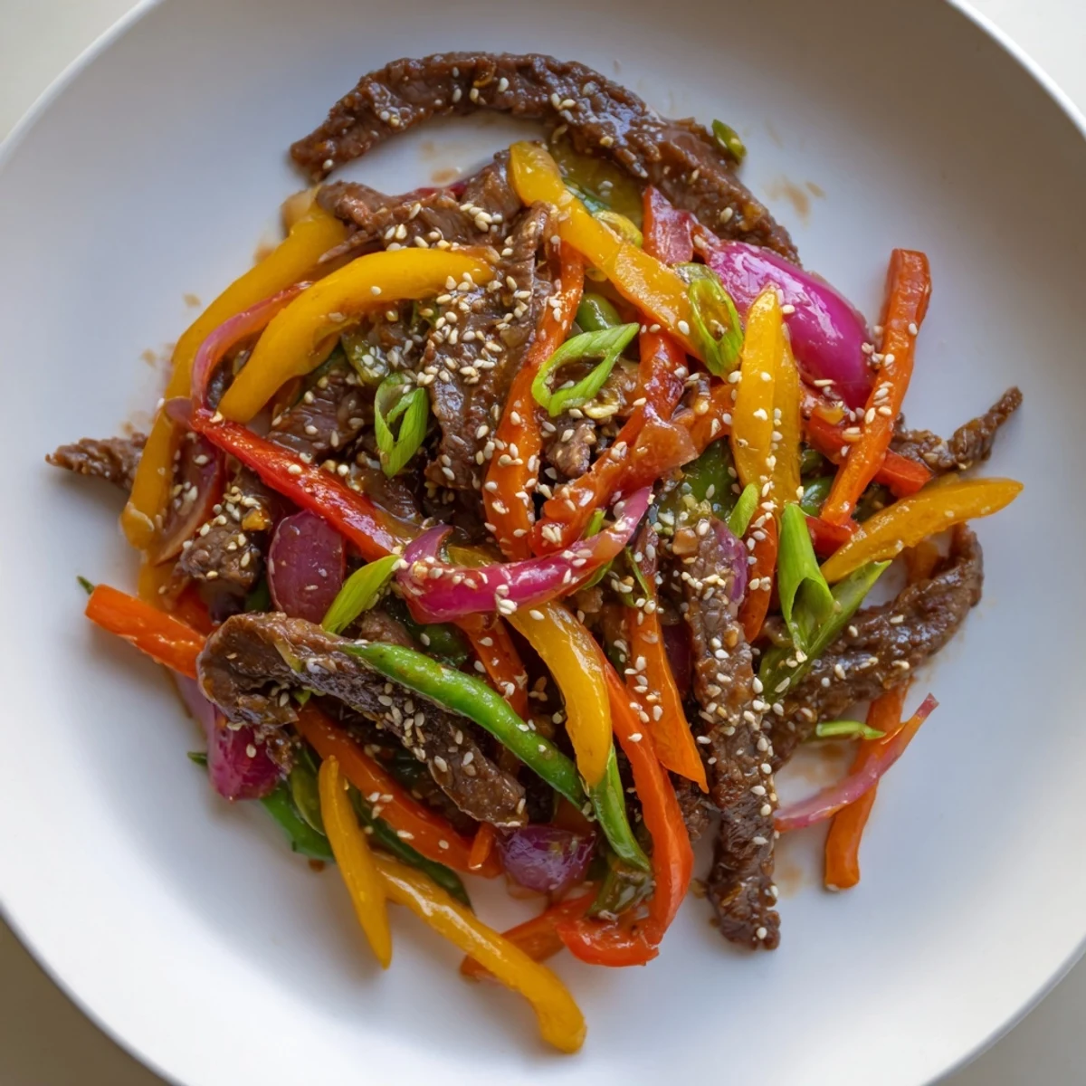 A close-up of Spicy Beef Stir Fry with Vegetables in a wok, featuring colorful crisp bell peppers and tender beef strips glistening with a glossy chili garlic sauce.