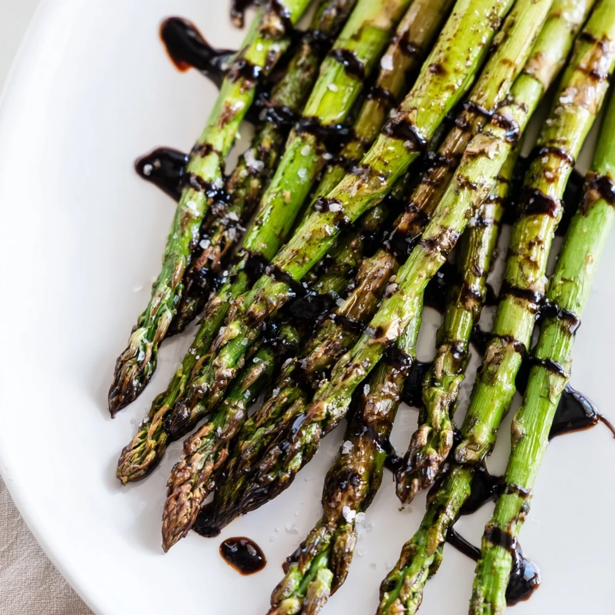 Roasted asparagus with balsamic glaze drizzled over spears, served warm as a vegetable side.