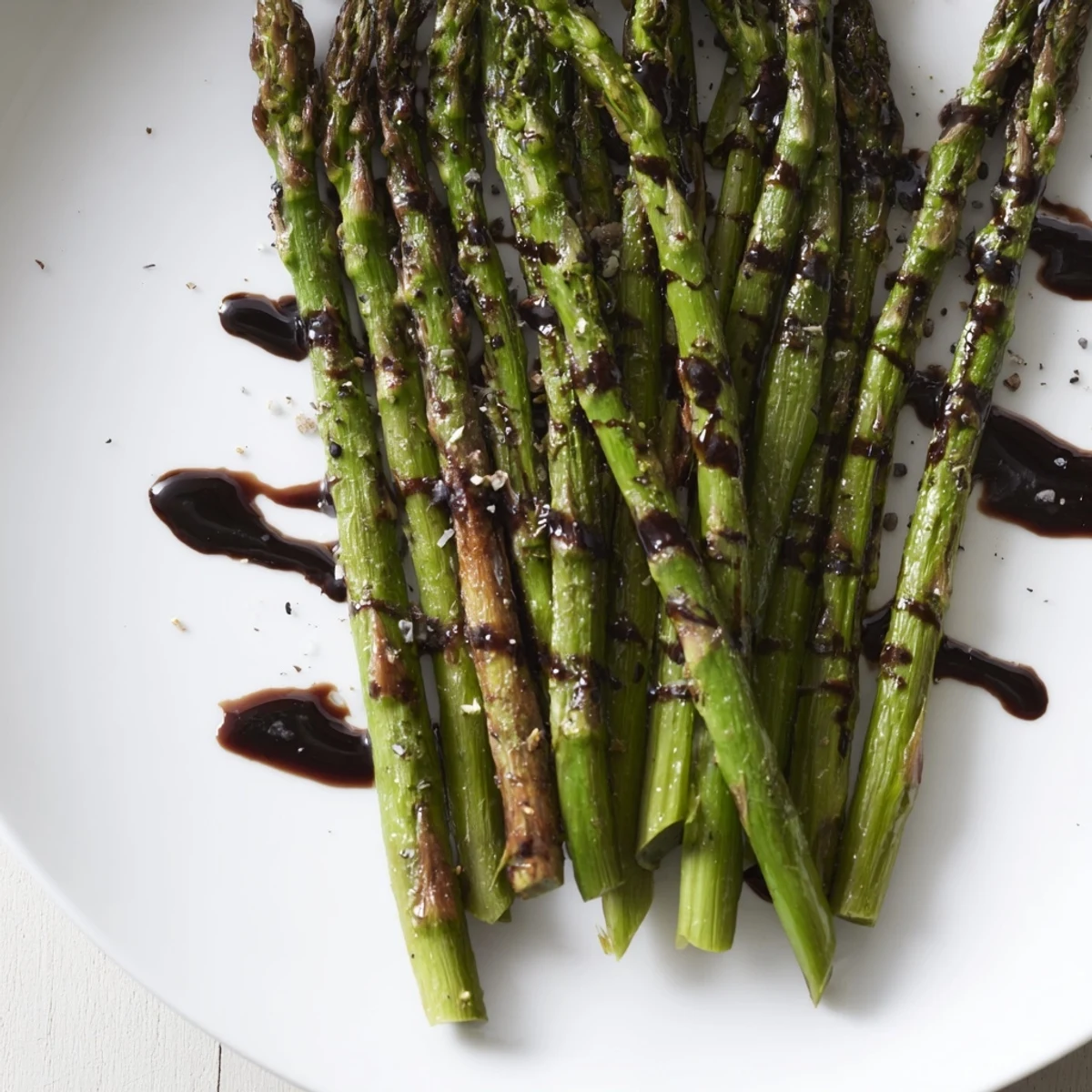 Roasted asparagus with balsamic glaze garnished with pine nuts, served on a rustic wooden table.