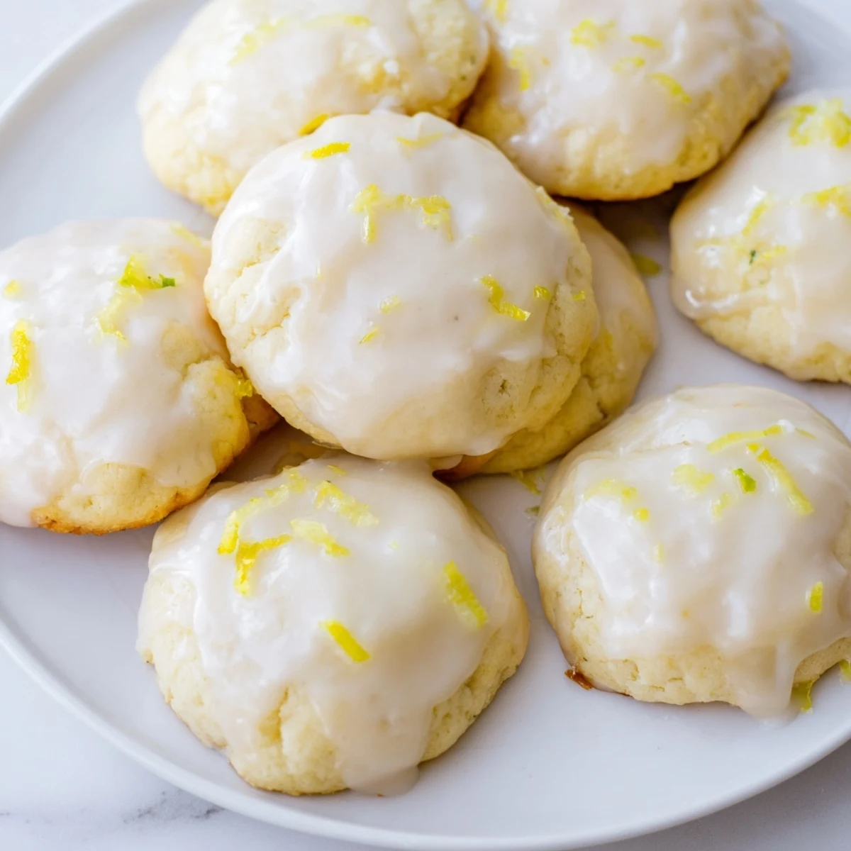 A close-up of soft Lemon Ricotta Cookies with Glaze drizzled over each cookie, showing moist crumbs and a sweet shine.