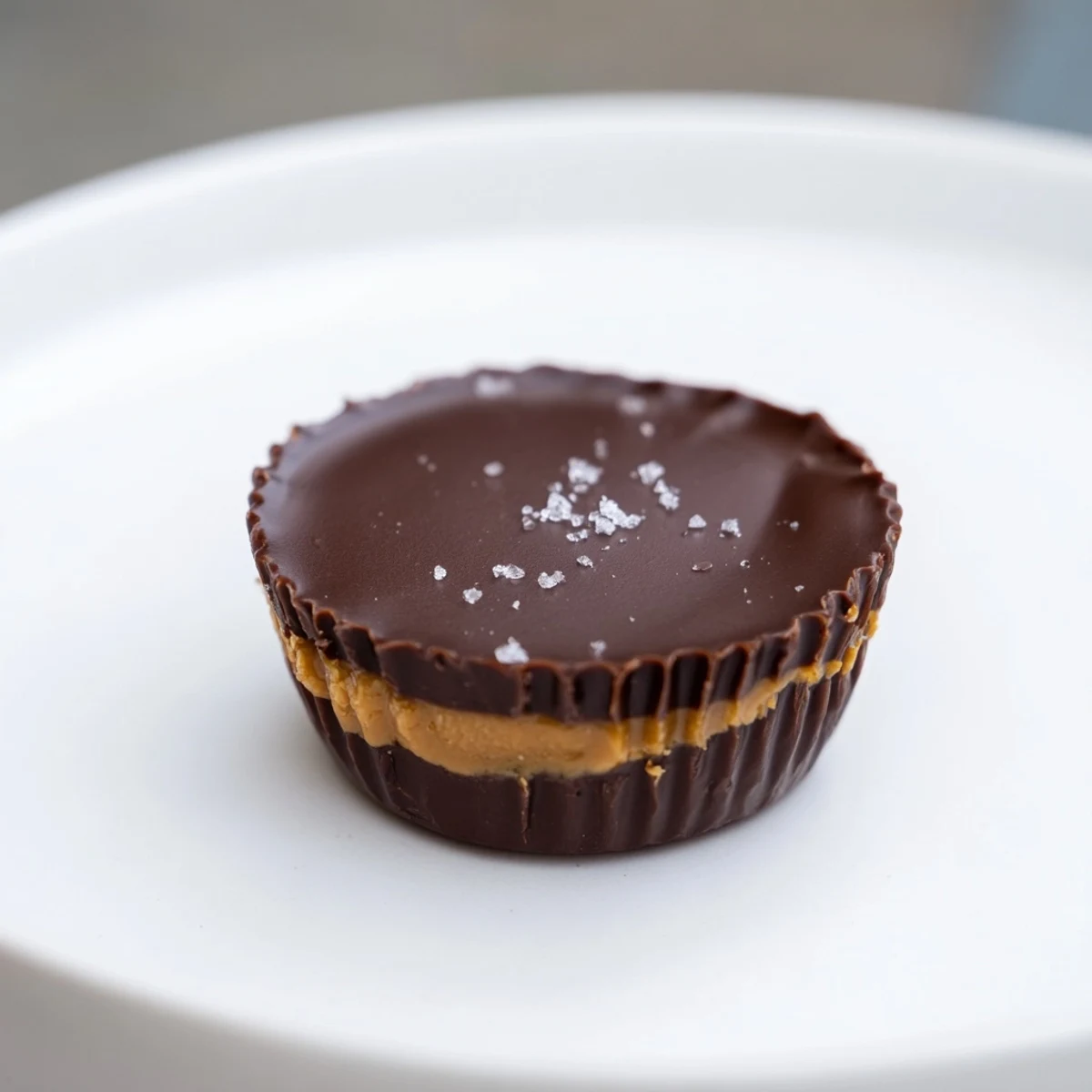 A platter of chocolate peanut butter cups, some with flaky sea salt on top, ready to be served as a classic American dessert treat.