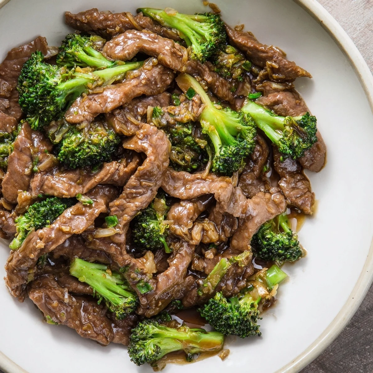 A close-up of Beef and Broccoli with Soy Sauce, showing tender beef strips and crisp broccoli coated in glossy sauce, served over steamed rice in a white bowl.