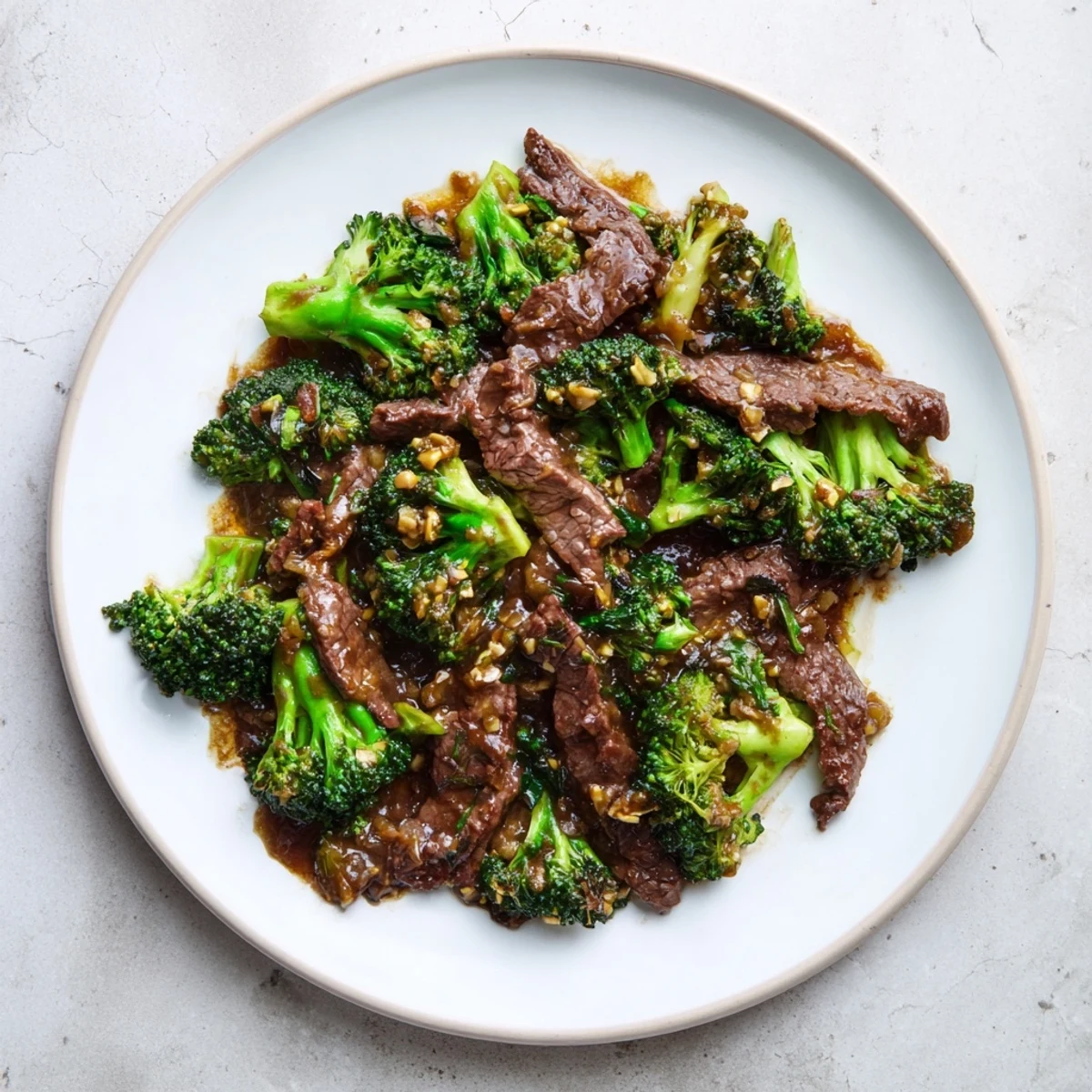 Steaming plate of Beef and Broccoli with Soy Sauce, featuring vibrant green broccoli florets beside seared beef slices, with a drizzle of savory sauce on top.