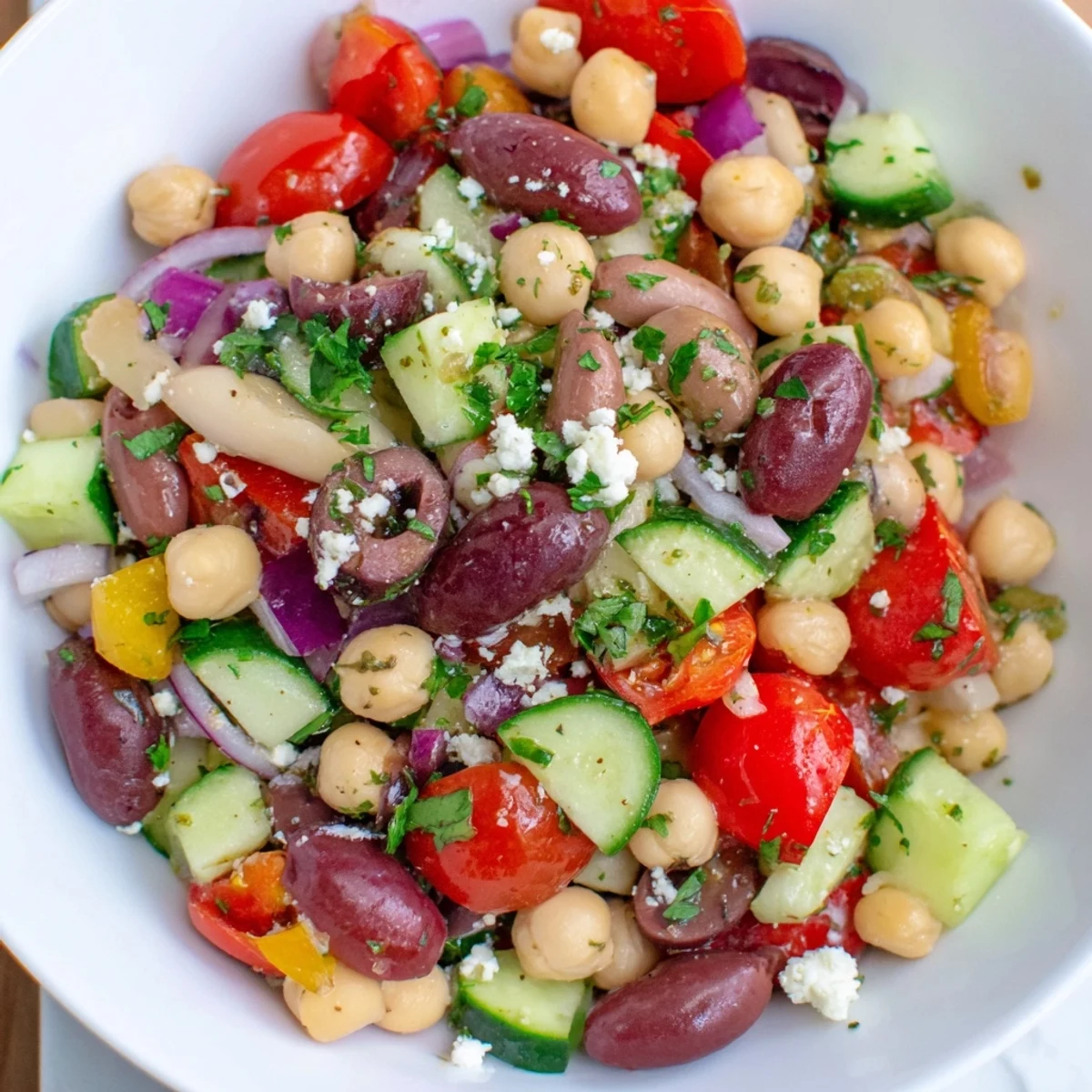 A vibrant Mediterranean Dense Bean Salad in a white bowl, with lemon dressing and fresh parsley garnish.