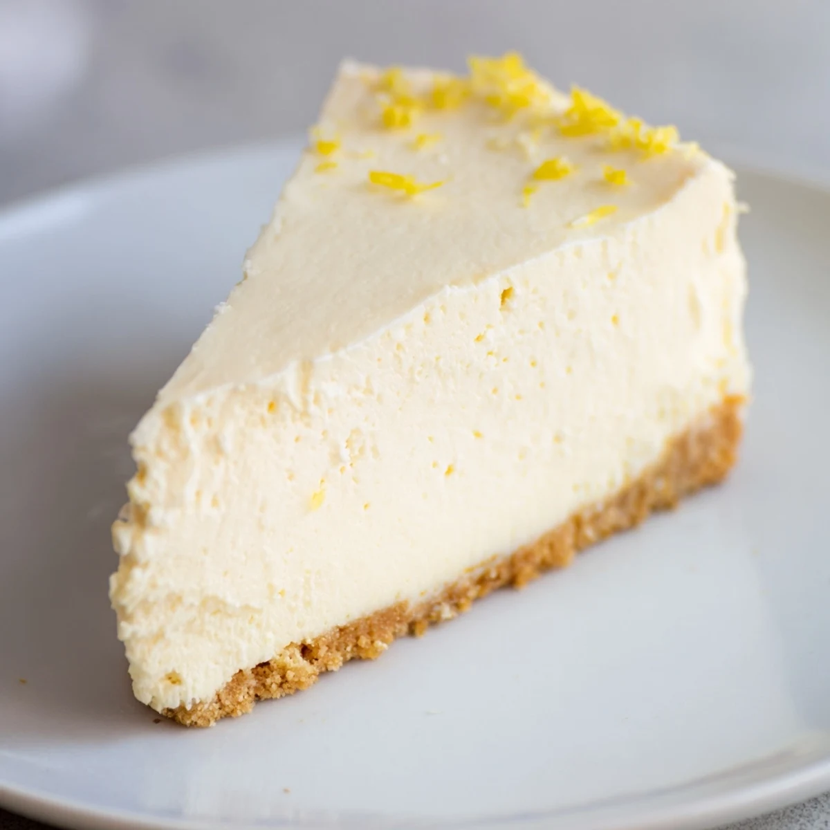 Close-up of Rich Greek Yogurt Cheesecake showing smooth, velvety texture and a dollop of sour cream.