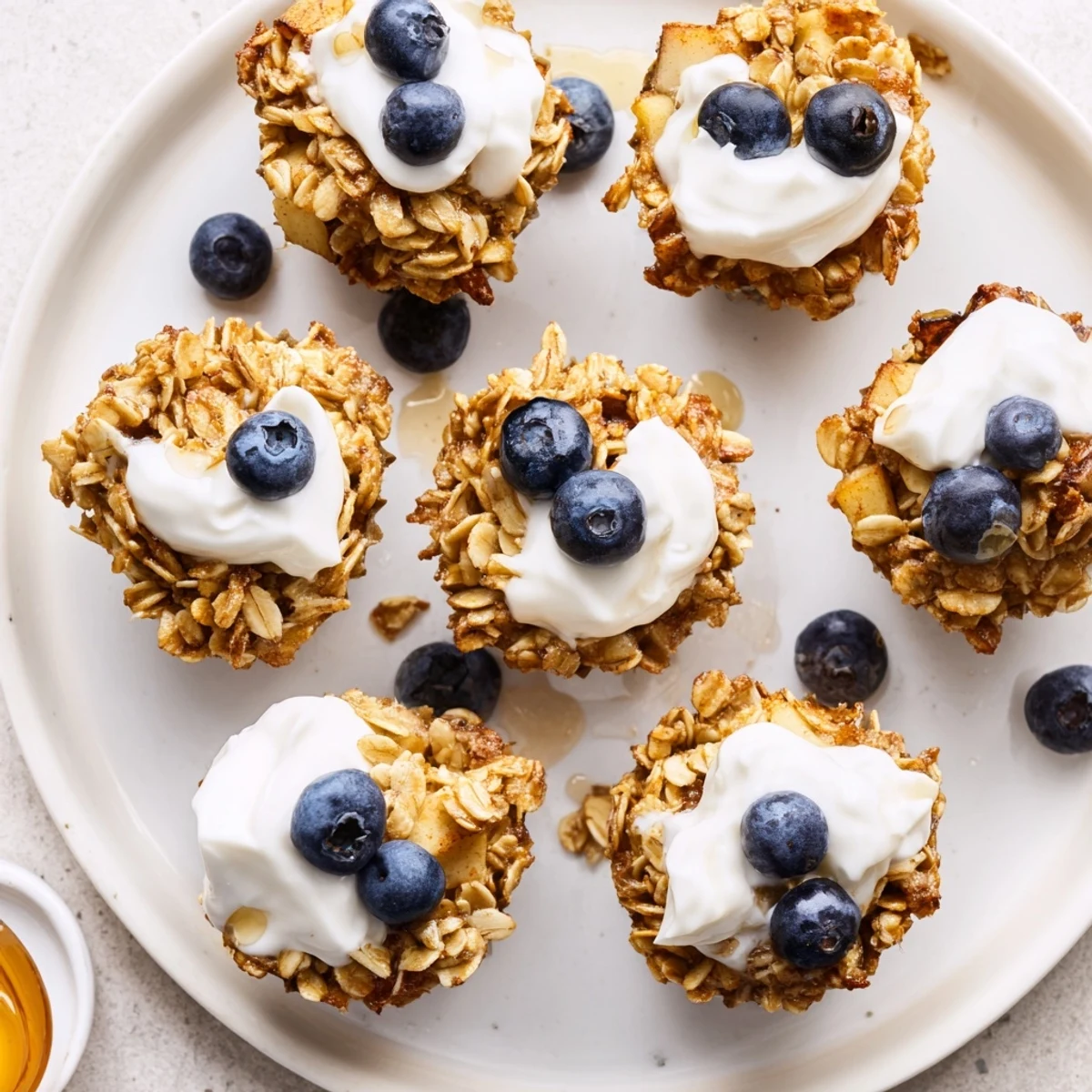 Freshly baked Baked Oatmeal Cups with Greek Yogurt sit on a wire rack, drizzled with honey and sprinkled with cinnamon.