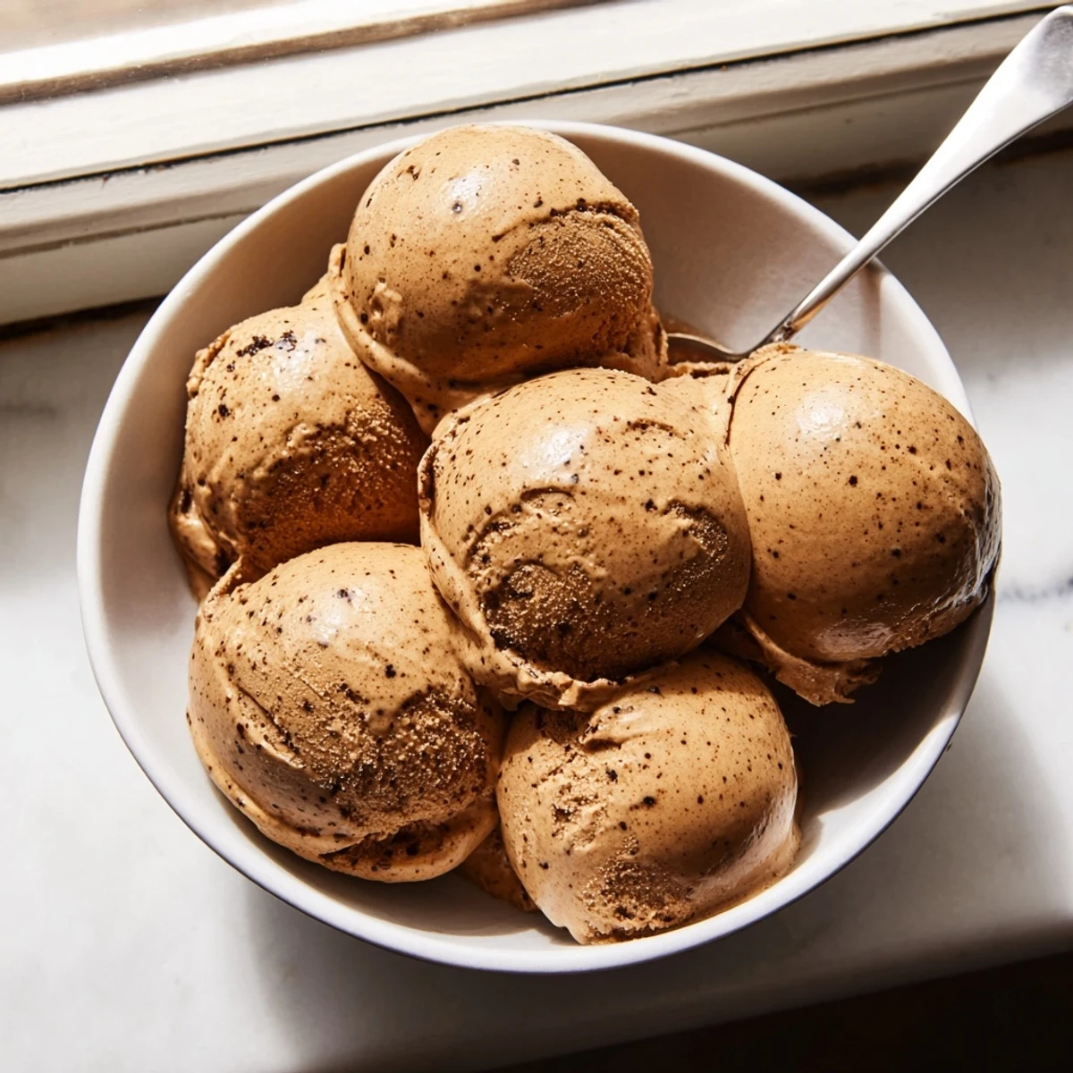 A close-up of rich, creamy Vietnamese Coffee Ice Cream scooped into a chilled ceramic bowl.