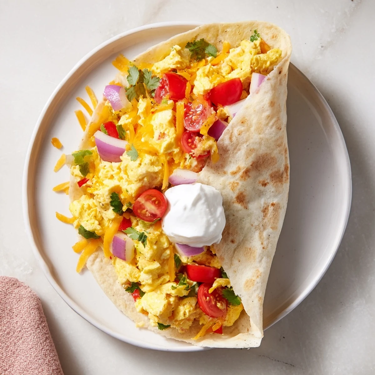 Overhead view of Tex Mex Egg Tortilla Pockets on a plate, garnished with fresh cilantro and sliced avocado.