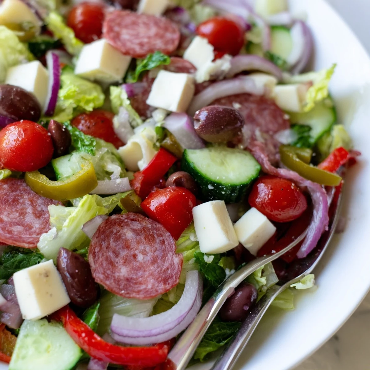 Colorful Italian chopped salad bowl with romaine, salami, mozzarella, olives and tangy homemade dressing