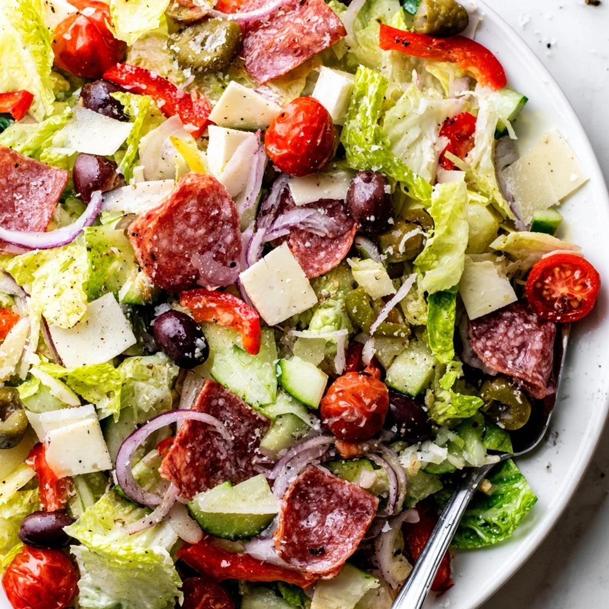 Vibrant bowl of Italian chopped salad tossed with homemade dressing, salami, olives, and fresh vegetables