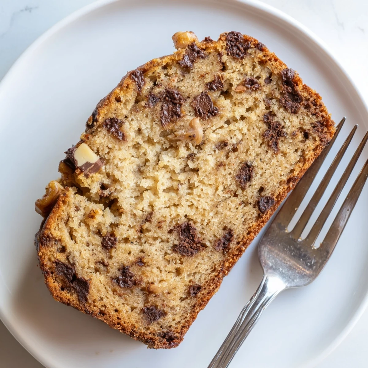 Freshly baked chocolate chip banana bread cooling on wire rack with golden crust and chocolate pockets