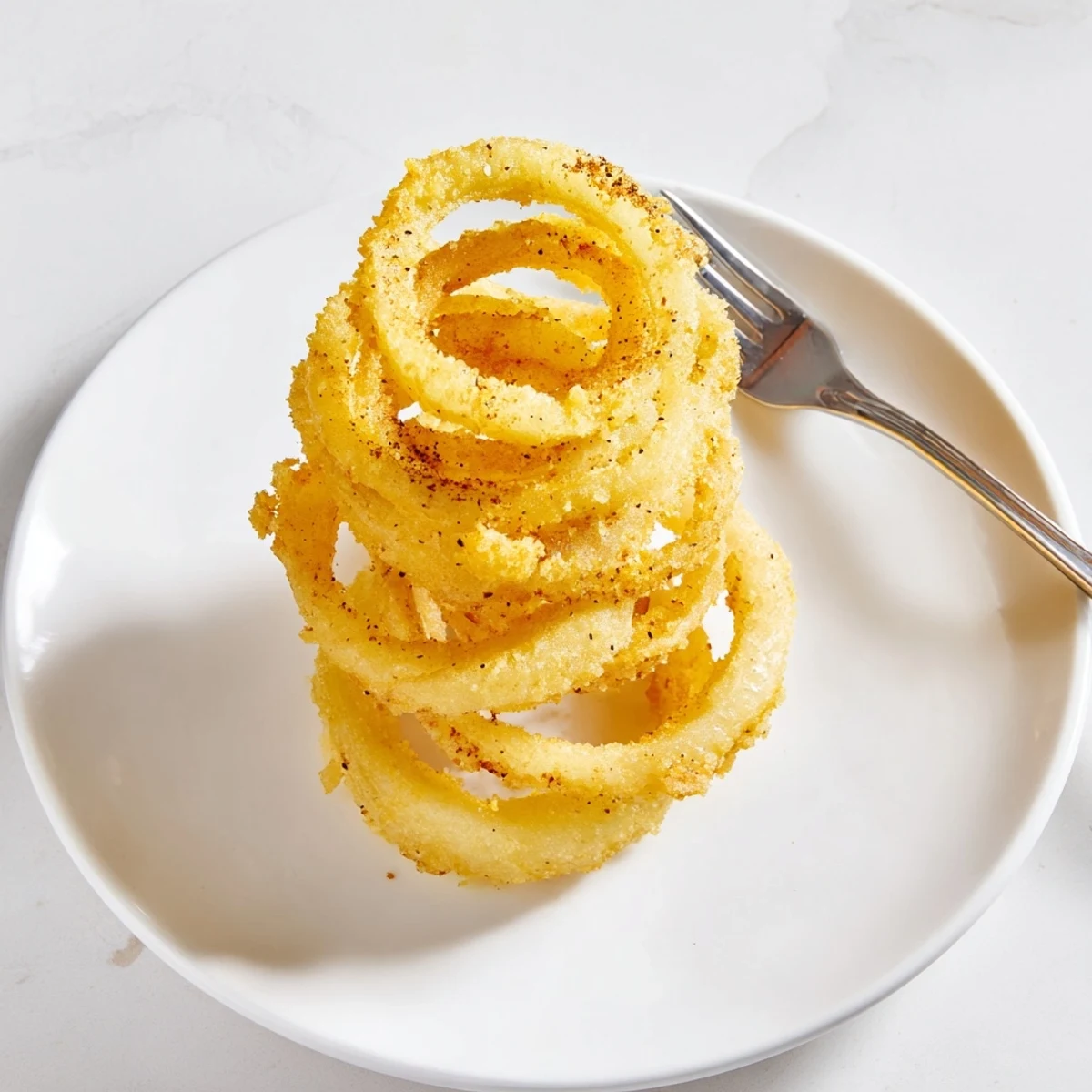 Golden brown onion ring chips arranged on a serving plate with dipping sauce