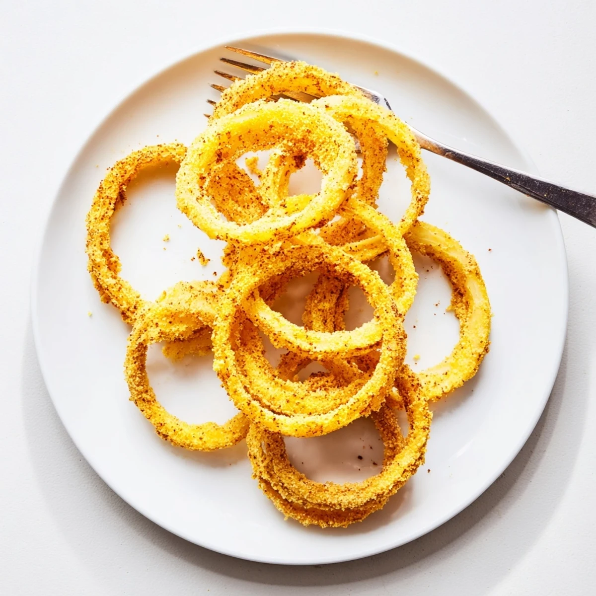 Ultra-thin crispy onion rings fried to golden perfection on a white platter