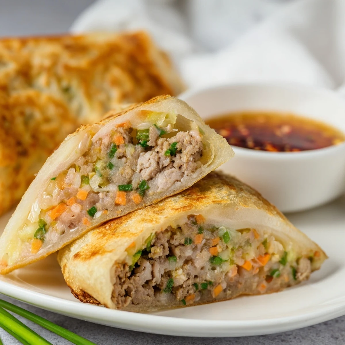 Fluffy pancakes stuffed with seasoned pork and vegetables served with dipping sauce on white plate