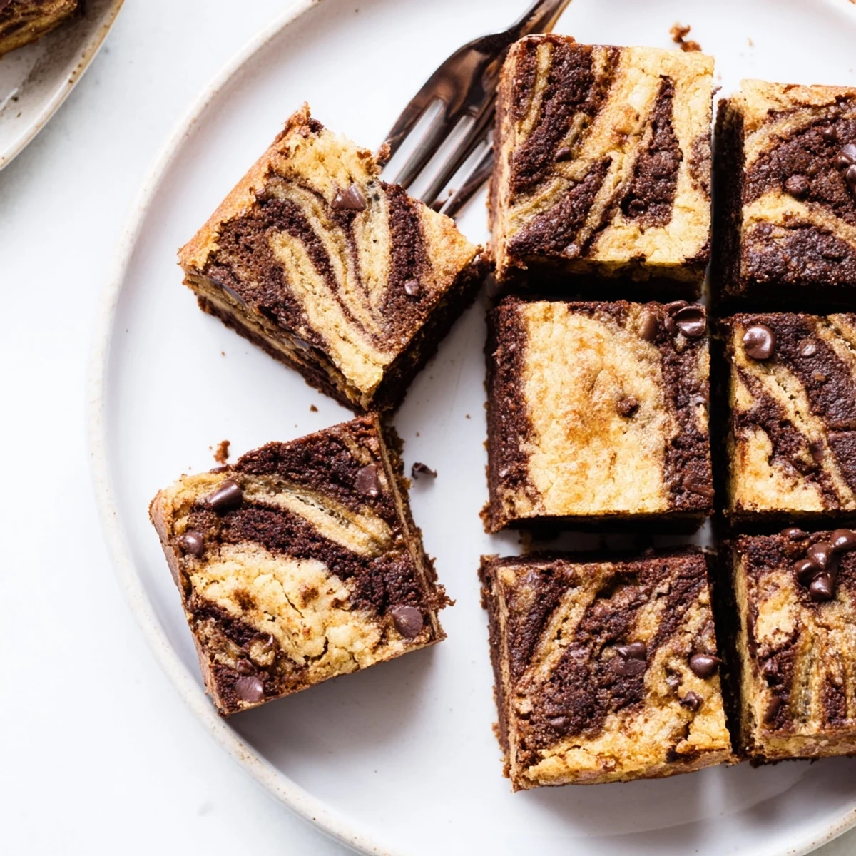 Freshly baked banana bread brownie bars with swirled chocolate and banana layers on a wooden cutting board