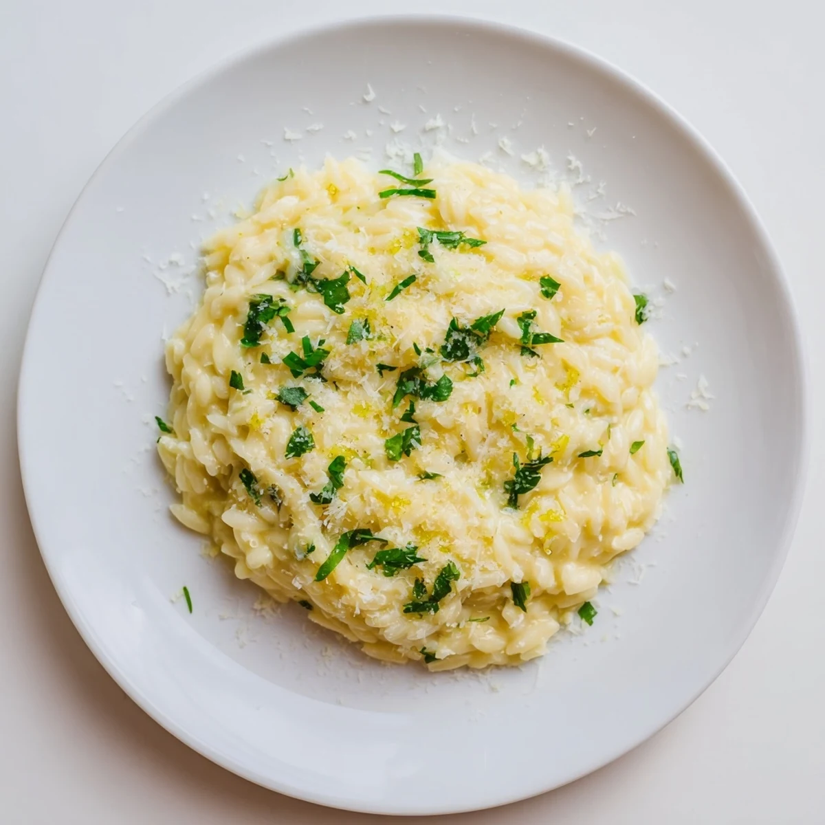 Golden lemon orzo with vibrant green herbs and optional peas plated as a light vegetarian main