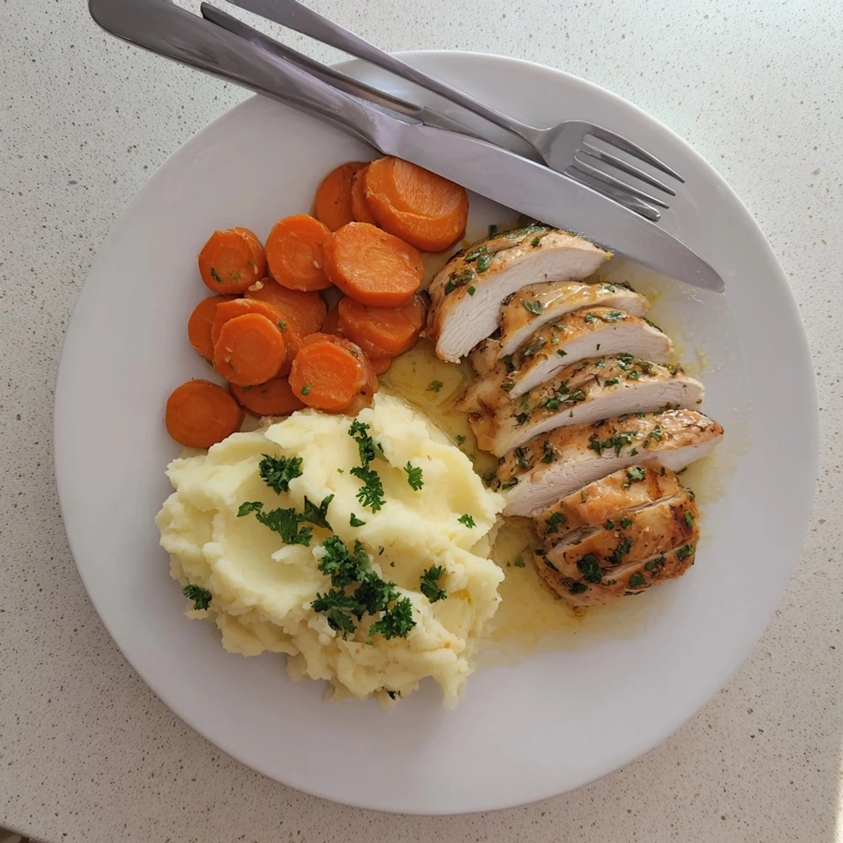 Tender marinated chicken resting on smooth mashed potatoes with vibrant honey glazed carrots garnished with fresh parsley