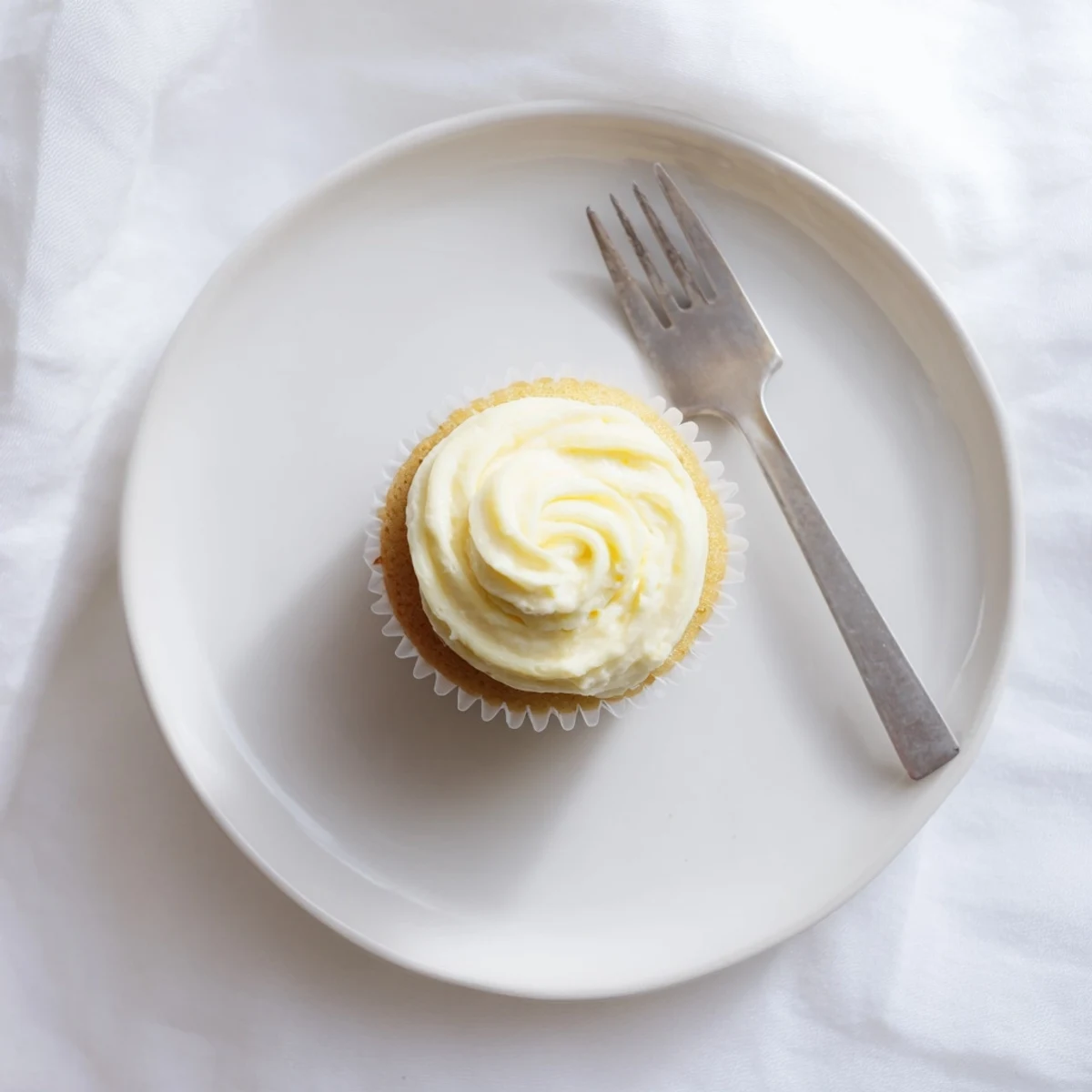 Freshly baked vanilla cupcakes topped with fluffy vanilla buttercream frosting and colorful sprinkles