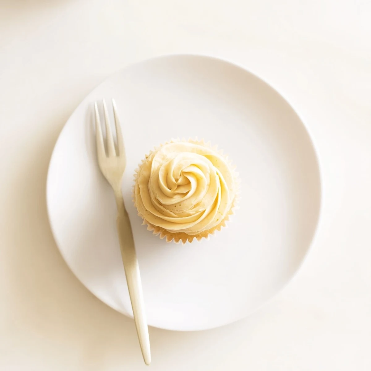 Golden vanilla cupcakes cooling on a wire rack with a vintage piping bag nearby