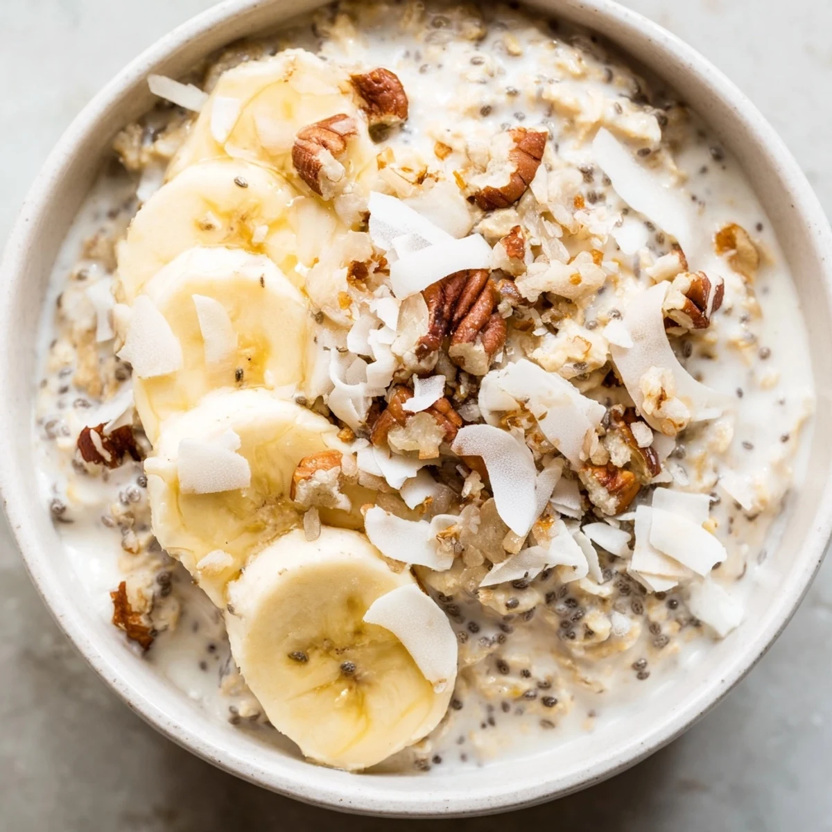 Creamy coconut cream pie overnight oats topped with toasted coconut and banana slices