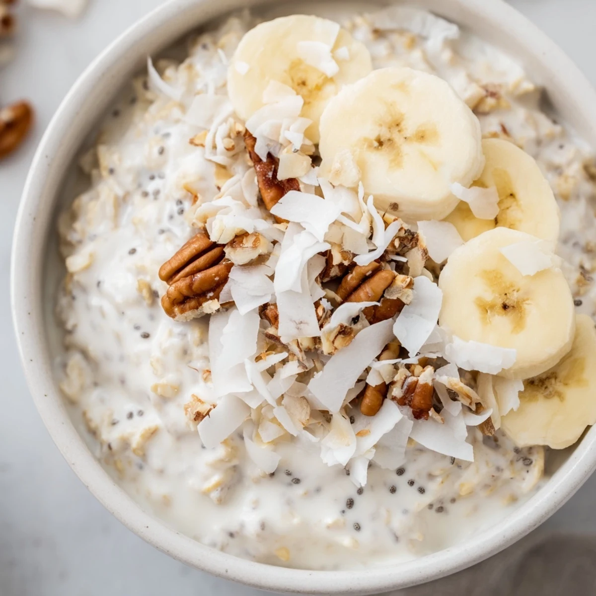 Thick coconut cream pie overnight oats served chilled with shredded coconut and almonds