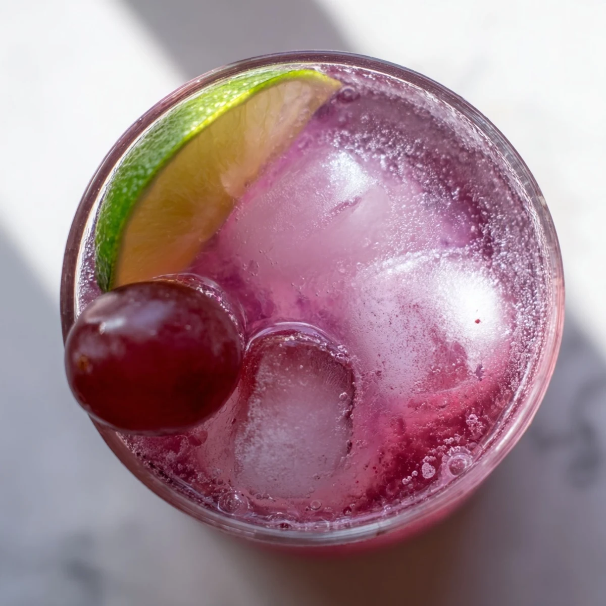 Pitcher of purple Grape Agua Fresca served over ice with fresh mint garnish