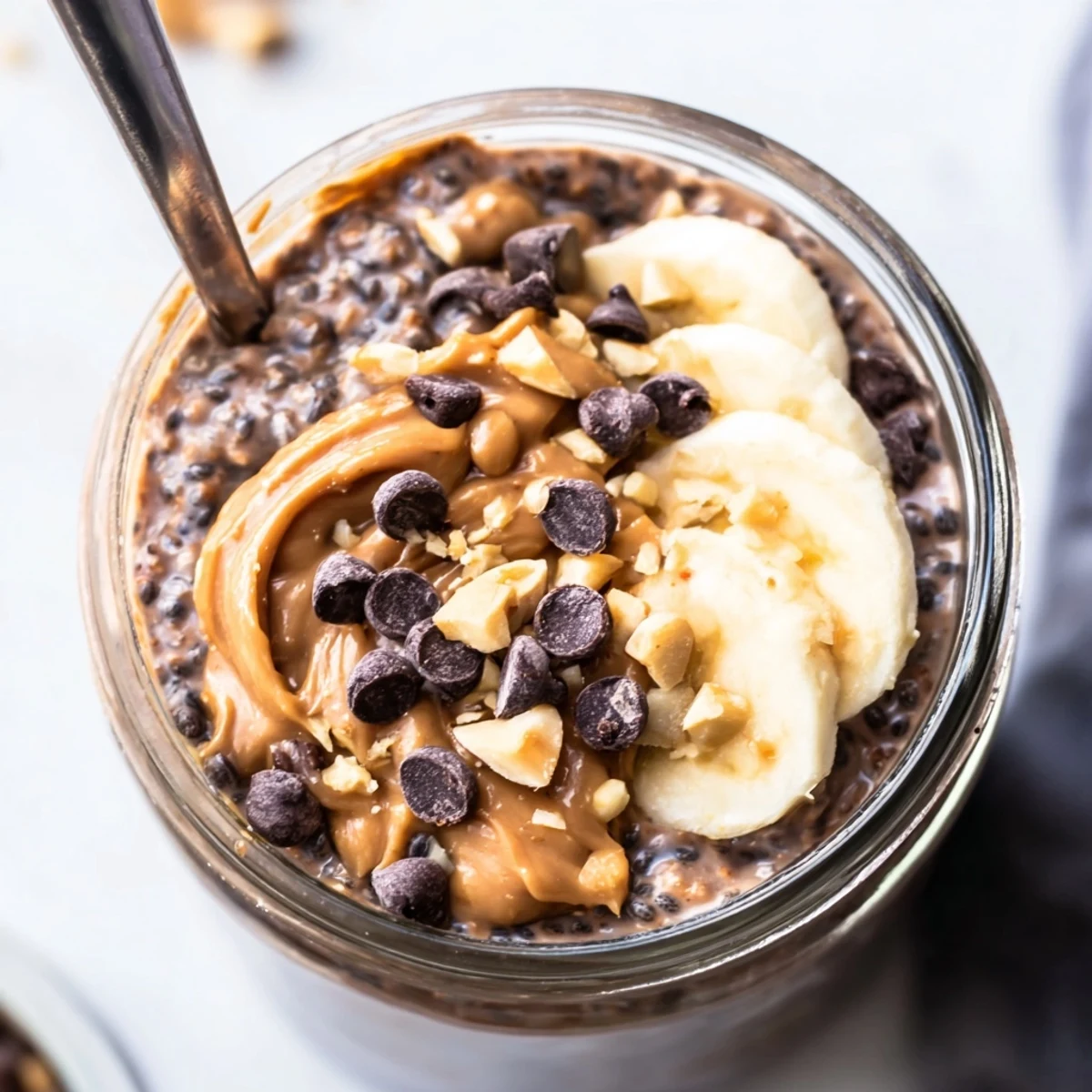 Creamy chocolate peanut butter overnight oats topped with chocolate chips and chopped peanuts in a mason jar
