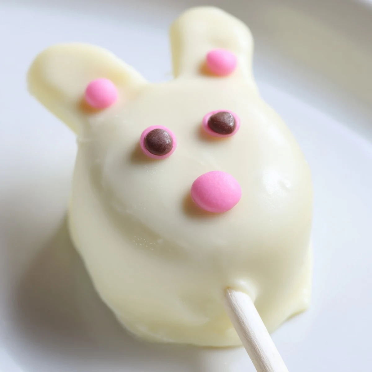 Adorable white chocolate bunny cakesicles with candy eyes on a festive Easter tray
