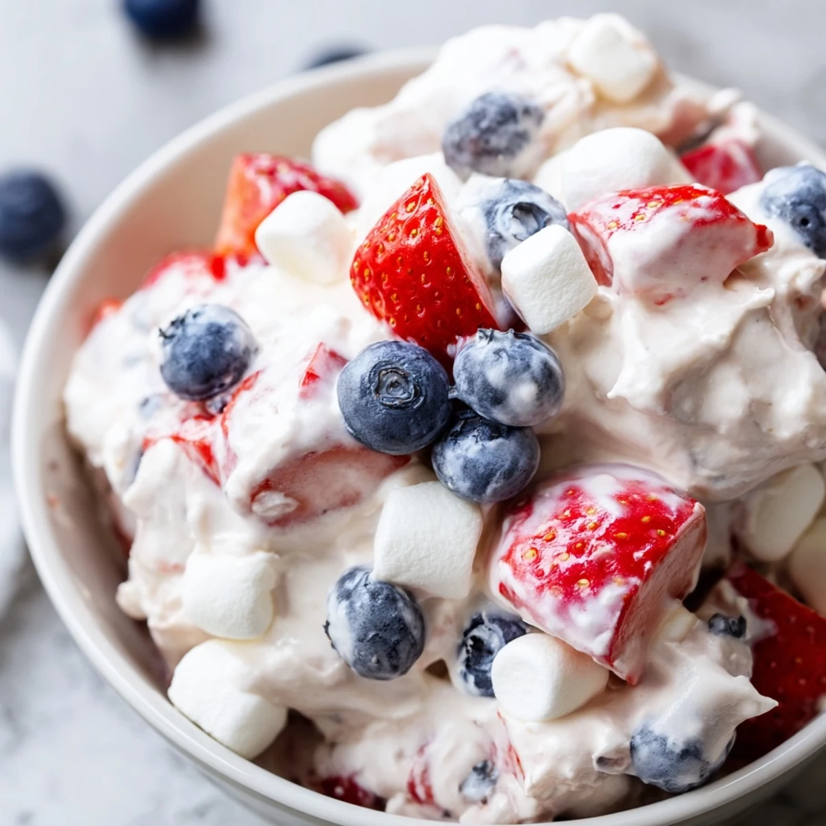 Vibrant Red White Blue Cheesecake Salad served chilled with juicy blueberries and fluffy whipped topping