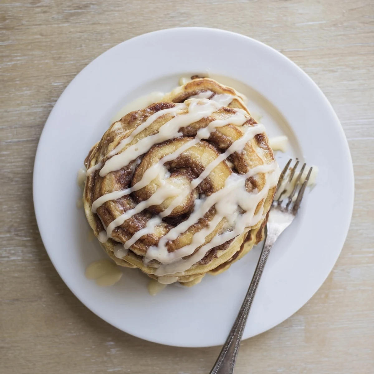 Fluffy cinnamon roll pancakes with spiraled brown sugar filling on a warm plate