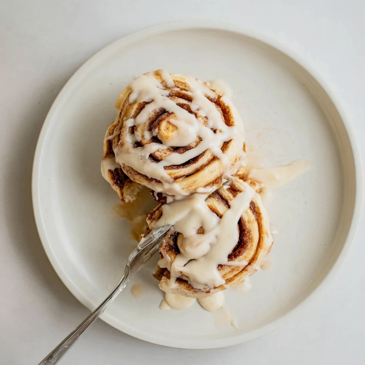 Golden cinnamon roll pancakes stacked high with rich cream cheese icing drizzle