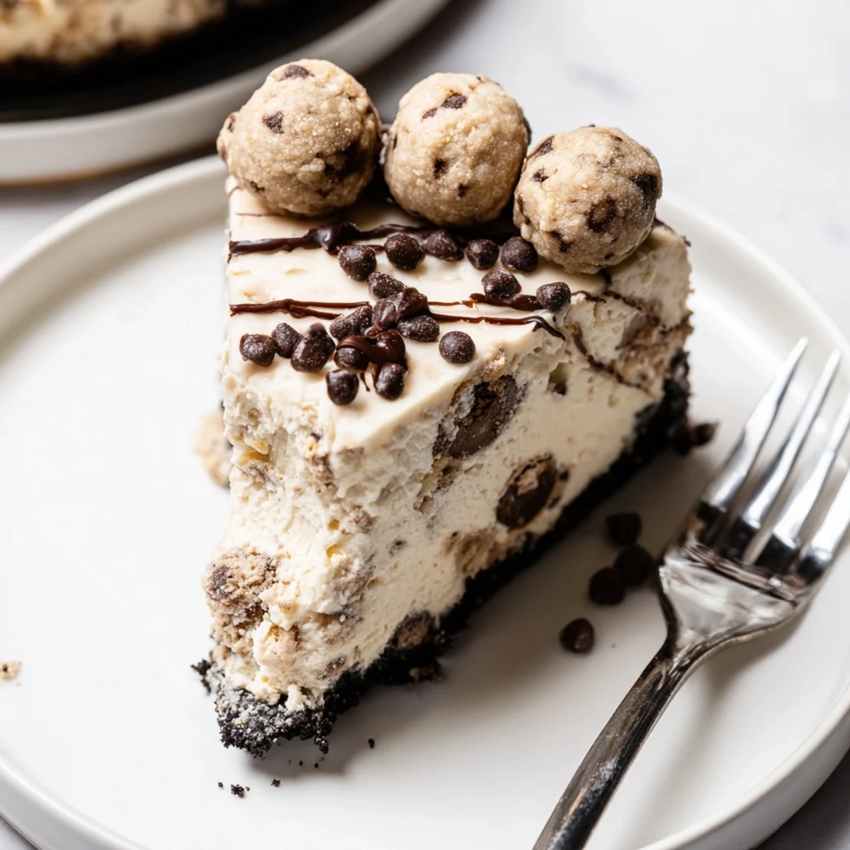 Fork-ready Chocolate Chip Cookie Dough Cheesecake plated with chocolate drizzle and chilled texture