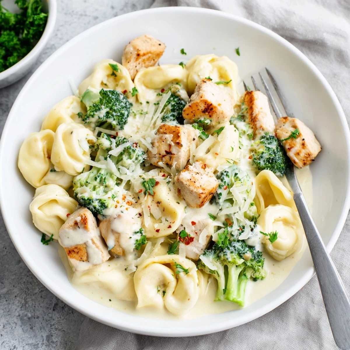 Steaming plate of silky tortellini and broccoli: Creamy Garlic Parmesan Tortellini Chicken Broccoli Recipe