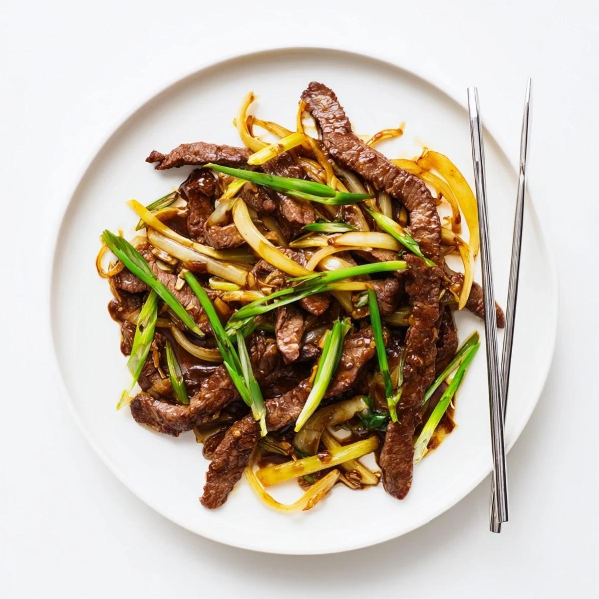 Savory Chinese-inspired crispy beef and onion stir fry sizzling in a dark wok with fresh green onion garnish