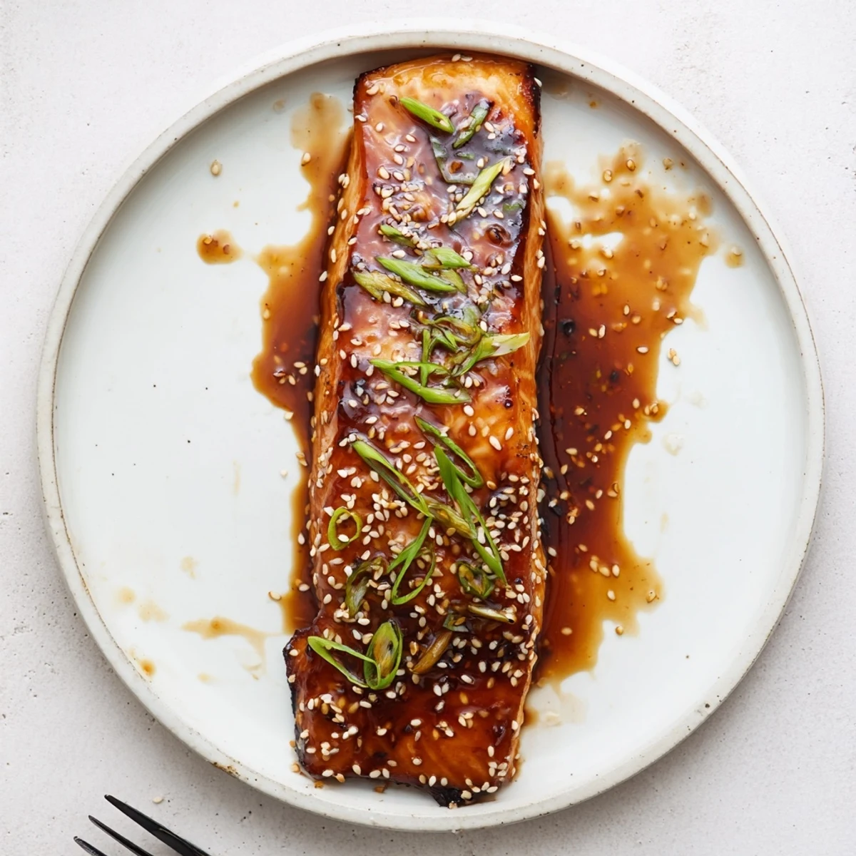 Glazed gluten free teriyaki salmon with sesame seeds on a white plate
