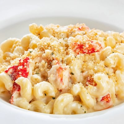 Creamy Lobster Mac and Cheese with Truffle Oil ready to serve, garnished with fresh parsley on a table.