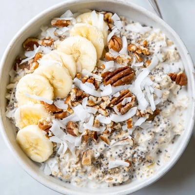 Coconut cream pie overnight oats layered in a jar with crunchy pecan topping