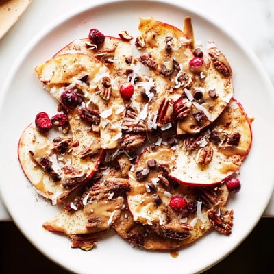 Thinly sliced crisp apples layered under warm cinnamon tahini drizzle and roasted nuts